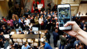 A visitor takes pictures as customers gather at a store selling Apple products during the launch of the new iPhone 7 sales at the State Department Store