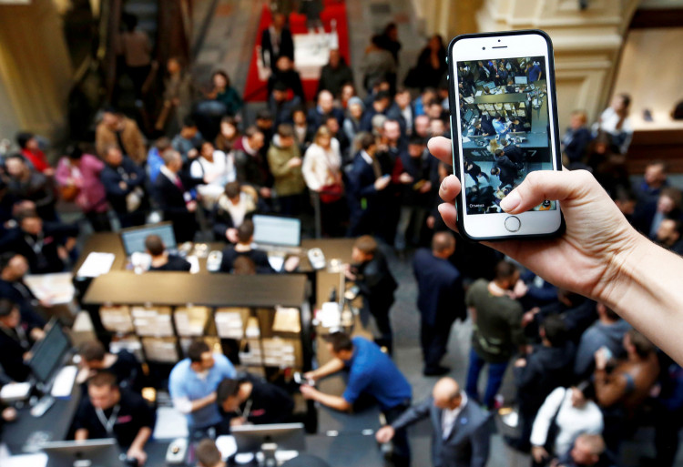 A visitor takes pictures as customers gather at a store selling Apple products during the launch of the new iPhone 7 sales at the State Department Store