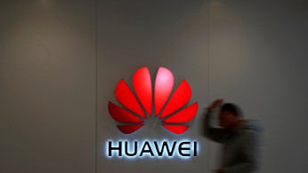 Man walks by a Huawei logo at a shopping mall in Shanghai