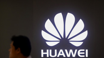 A man walks past a Huawei's company logo outside its shop in Bangkok