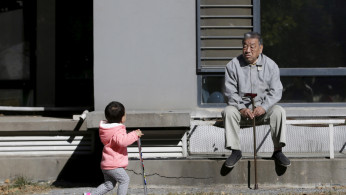 An 80-year-old man, surnamed Li, watches as a girl plays at a residential community in Beijing, China, October 30, 2015. 