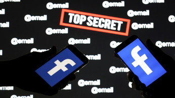 Persons hold smartphones with the Facebook logo in front of displayed 