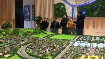 People listen to a sales agent at a real estate showroom of Yango Group