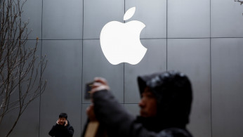 People use their phones outside an Apple store in Beijing