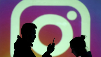 Silhouettes of mobile users are seen next to a screen projection of Instagram logo in this picture illustration