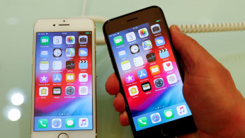 An employee of German Apple retailer Gravis displays an iPhone 7 and 8 in a store in Berlin, Germany