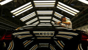 A worker stands next to a car on the assembly line as serial production of the new Audi TT roadster starts at the Audi plant in Gyor, west of Budapest