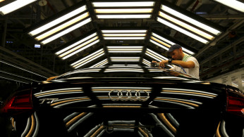 A worker stands next to a car on the assembly line as serial production of the new Audi TT roadster starts at the Audi plant in Gyor, west of Budapest
