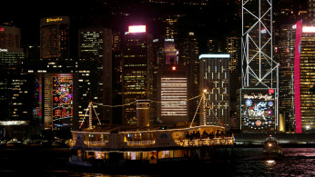 A ferry sails past commercial buildings with Christmas decorations in Hong Kong