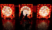 Woman pushes an elderly on a wheelchair past a pig-themed installation at a lantern fair on the second day of Chinese Lunar New Year of the Pig, at Wuhan Garden Expo