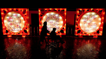 Woman pushes an elderly on a wheelchair past a pig-themed installation at a lantern fair on the second day of Chinese Lunar New Year of the Pig, at Wuhan Garden Expo