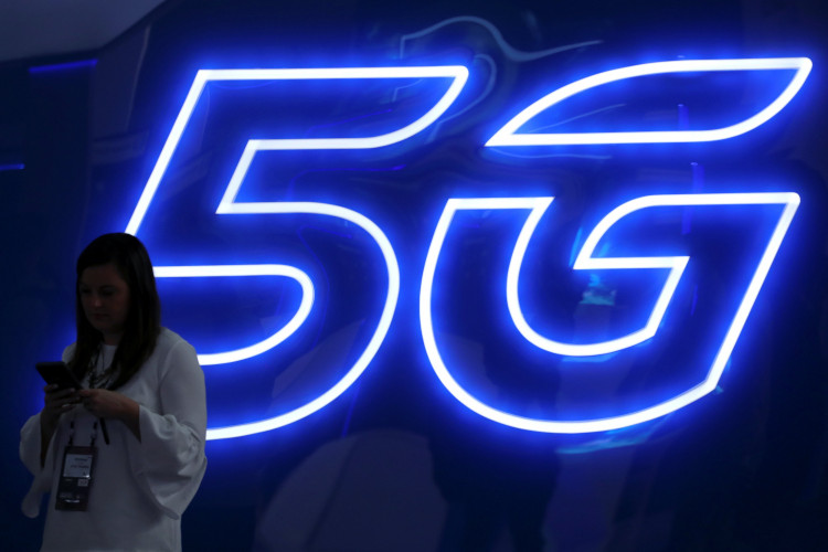 A woman looks at her mobile phone next to a 5G sign at the Mobile World Congress in Barcelona