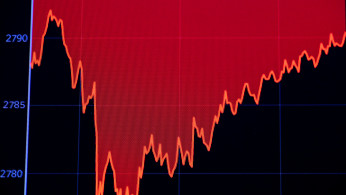 A screen displays a chart of the Dow Jones Industrial Average during trading on the floor of the NYSE
