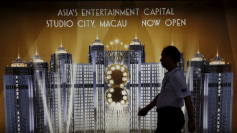 A man walks past an advertisement of Macau's Studio City resort