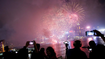 People take pictures as fireworks explode over Victoria Harbour to celebrate the Lunar New Year