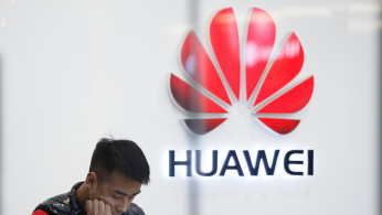 A staff member stands in front of a Huawei shop in Beijing