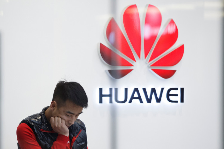 A staff member stands in front of a Huawei shop in Beijing