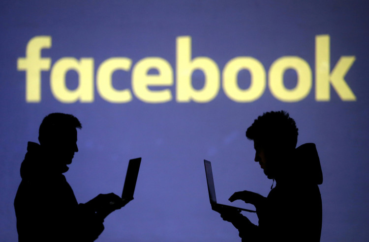  Silhouettes of laptop users are seen next to a screen projection of Facebook logo in this picture illustration
