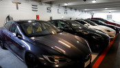 Tesla Model 3 and model X cars charging in a parking lot next to a Tesla store in San Diego