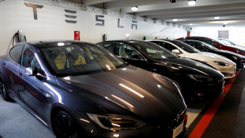 Tesla Model 3 and model X cars charging in a parking lot next to a Tesla store in San Diego