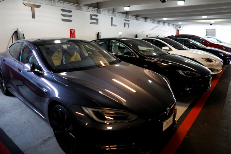 Tesla Model 3 and model X cars charging in a parking lot next to a Tesla store in San Diego