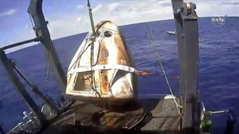 An unmanned capsule of the SpaceX Crew Dragon spacecraft as it was lifted out of the ocean and loaded on the recovery ship in the Atlantic Ocean