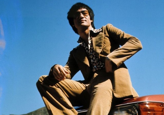 Bruce Lee looking fly on his red Mercedes-Benz 450SL in the 1970s.