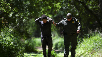 A U.S. Border Patrol agent apprehends an undocumented man from Honduras after he illegally crossed the U.S.-Mexico border in Mission