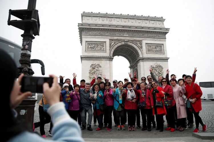 Chinese tourists pose for photos in front of the Arc de Triomphe on the Champs-Elysees avenue during the Act XIX (the 19th consecutive national protest on a Saturday) of the "yellow vests" movement in Paris, France, March 23, 2019. 