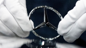 An employee wipes the logo on a car at the Mercedes Benz automobile assembly plant outside Moscow