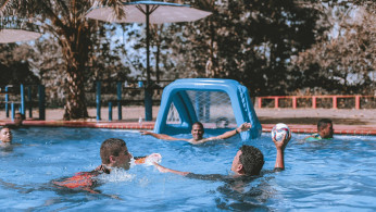 People on Swimming Pool Playing Ball