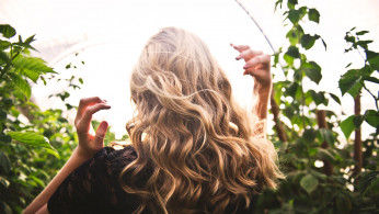Blond Haired Woman Standing Between Green Plants