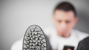 Man sitting beside the wall wearing sneakers