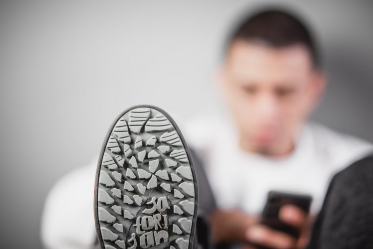 Man sitting beside the wall wearing sneakers