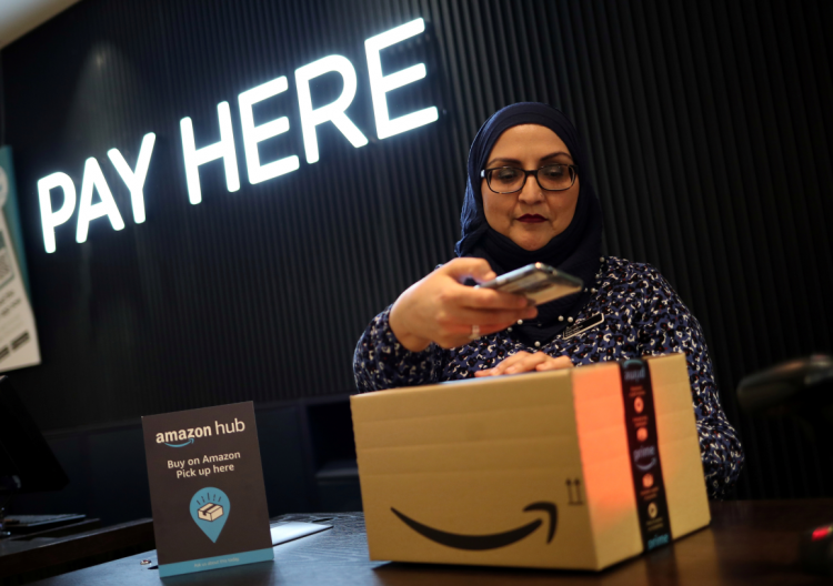 An employee demonstrates Amazon Counter, a click and collect service allowing customers to collect their Amazon parcels in-store at a Next store 