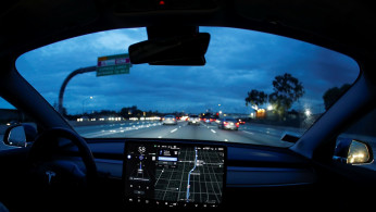 A Model 3 Tesla vehicle navigates morning rush hour using the car's auto pilot feature in Los Angeles