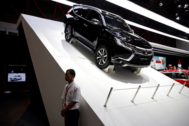 A worker stands near Mitsubishi Pajero Sport on display at the Indonesia International Motor Show in Jakarta