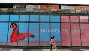 Women walk past a Huawei P30 advertising LED board at a shopping centre in Bangkok