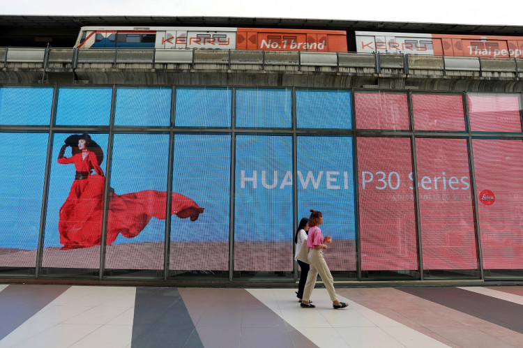 Women walk past a Huawei P30 advertising LED board at a shopping centre in Bangkok