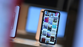 Front pages of newspapers and magazines are displayed on an iPhone during the grand opening and media preview of the new Apple Carnegie Library store in Washington
