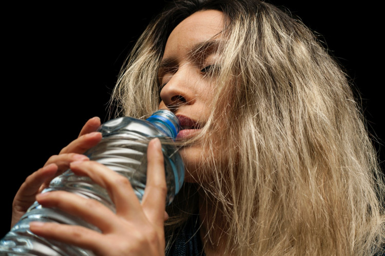 woman holding a plastic water bottle