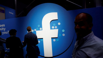 FILE PHOTO: Attendees walk past a Facebook logo during Facebook Inc's F8 developers conference in San Jose, California, United States