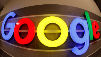 An illuminated Google logo is seen inside an office building in Zurich