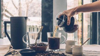 A person filling a mug with coffee
