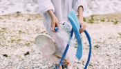 Person holding a plastic bottle in the beach.