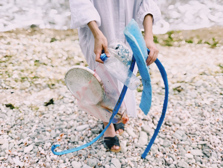 Person holding a plastic bottle in the beach.