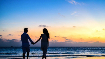 Man and woman holding hands beside the sea.