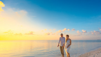Couple Walking on Seashore During Sunset