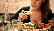 Woman Eats Alone As She Holds Sliced Pizza.