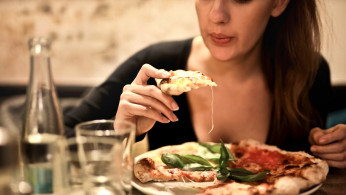 Woman Eats Alone As She Holds Sliced Pizza.